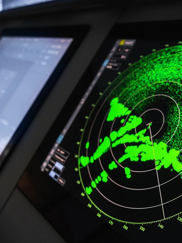 Close-up of a radar screen showing green signals and circular grid lines.