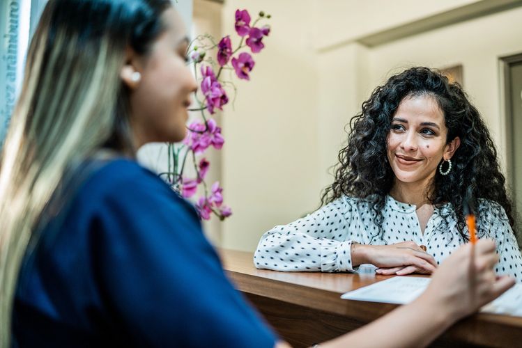 Dental receptionist talking with a patient at the front desk.