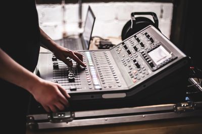 Person adjusting controls on a sound mixing console.
