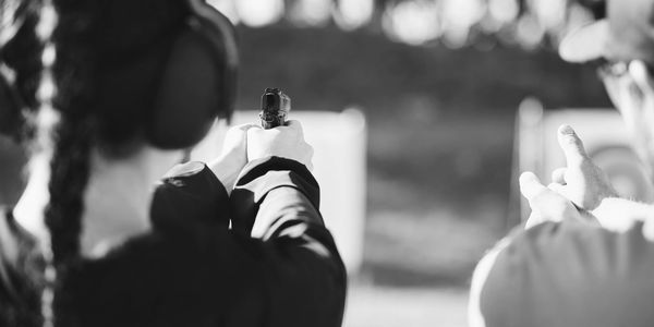 Person aiming a handgun at a shooting range with instructor guidance. Texas License to carry and national firearms course instruction. 