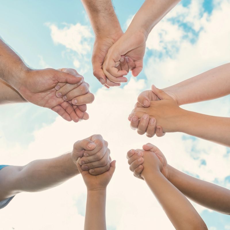 Joined hands as a team. Business teamwork. Close up group of friends meeting join hands together. Diversity people. Partnership volunteer community. Diverse multiethnic Partners. Blue Sky background. collaboration. Summer vacation. Family travel.