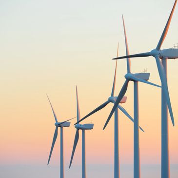 Row of wind turbines at sunset against a pastel sky.