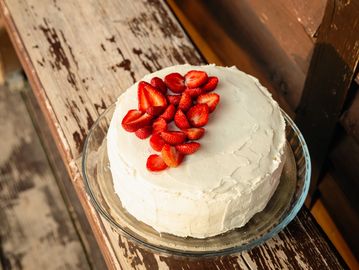 White frosted cake topped with fresh strawberries.
