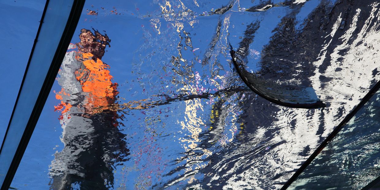 Reflection of a person walking on water seen through a glass floor.