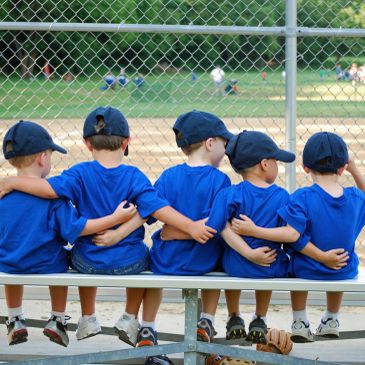 Young boys in blue baseball uniforms sitting together on a bench.