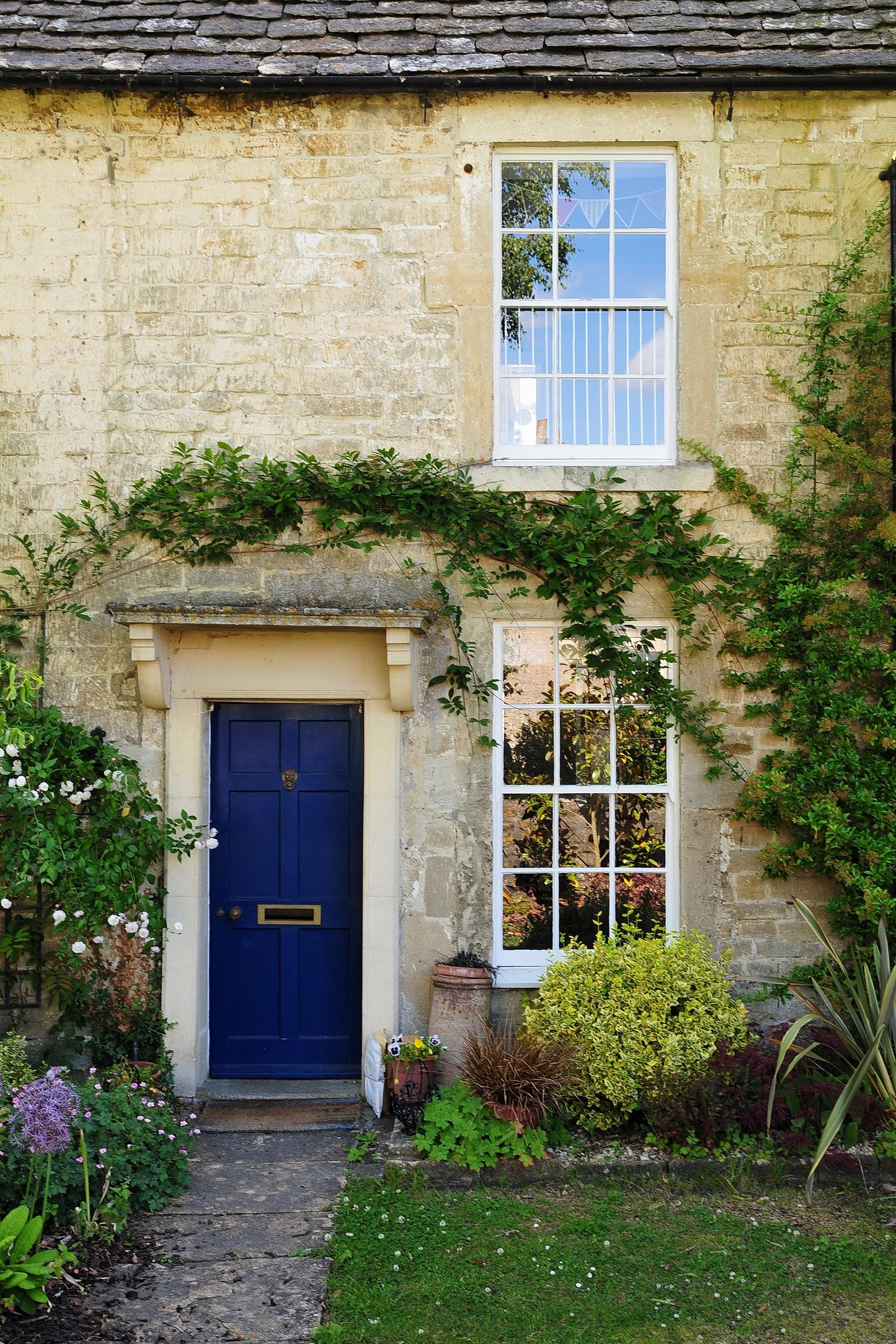 Charming stone cottage with a vibrant blue door and lush garden.