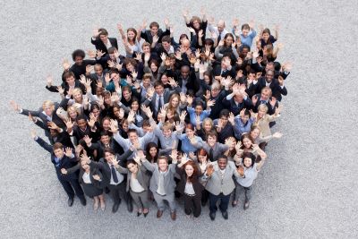 Large diverse group of people smiling and waving at the camera.