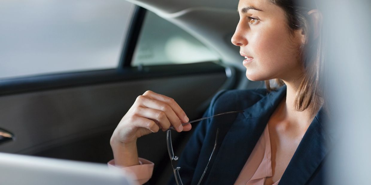 Woman sitting in a car looking thoughtfully out the window.