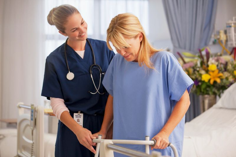 Nurse helping patient with walker in hospital room