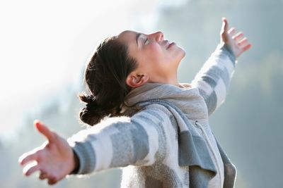 Woman enjoying fresh air with arms outstretched in nature.