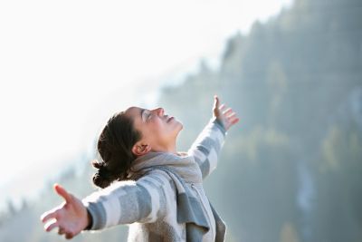 Woman enjoying fresh air with open arms outdoors.