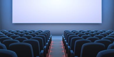 Empty movie theater with rows of seats facing a large blank screen.