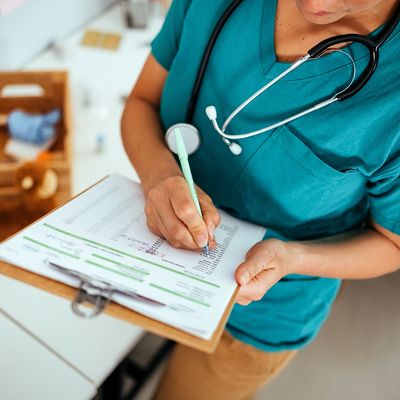 Healthcare professional filling out a medical form.