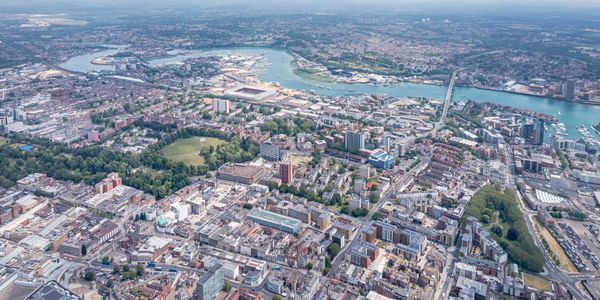 Aerial view of a city with buildings, a river, and green spaces.