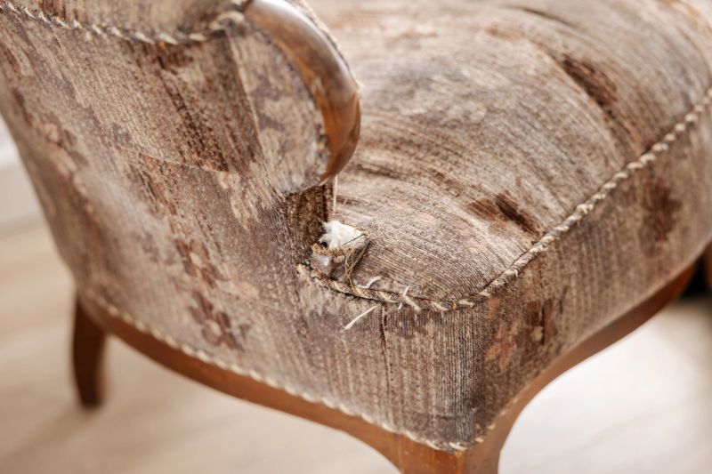 Old, damaged vintage armchair with holes in seat. Antique couch with ripped fabric. Upholstered furniture restoration service. Furniture repair