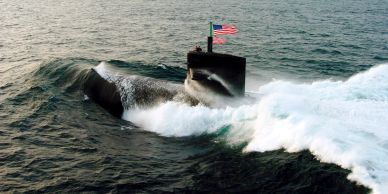 A submarine surfacing with an American flag on the ocean.