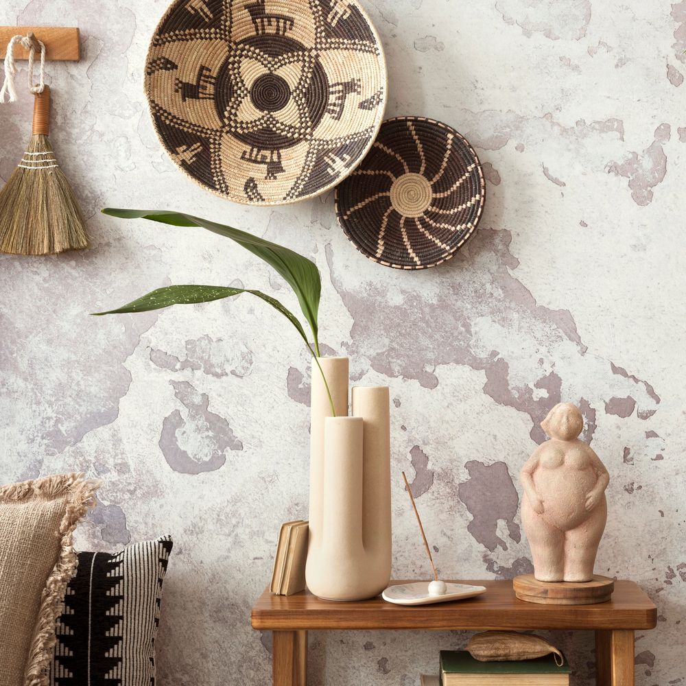 Boho-style decor with woven baskets, a unique vase, and a feminine sculpture on a wooden table.