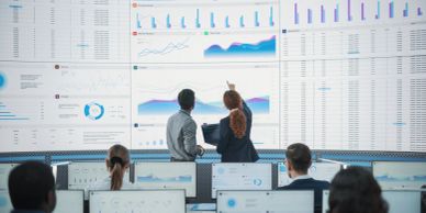 Team analyzing data visualizations on large digital screens.