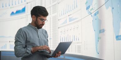 Man analyzing data on a laptop in front of charts.