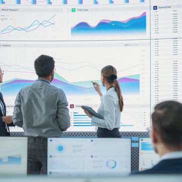 Business team analyzing charts on large screens.