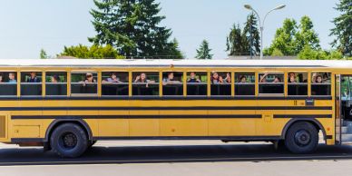 Children looking out from a yellow school bus.