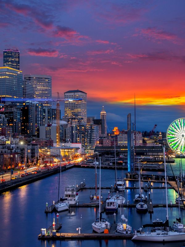 Seattle waterfront sunset with skyline, ferris wheel, and marina highlighting convention districts.