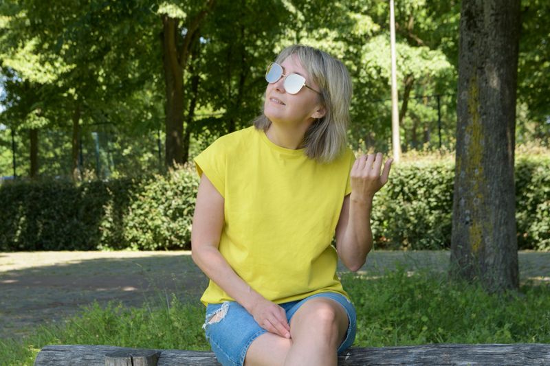 A blonde woman in sunglasses summer portrait of a against the backdrop of a trees in the park