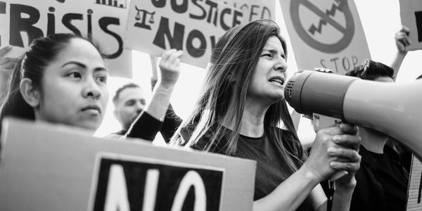 Women protesting with signs and megaphone.