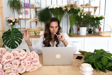 Woman working on a laptop in a flower shop.