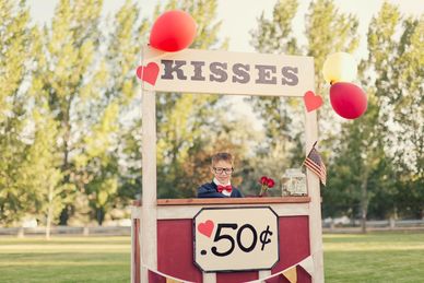 Young boy selling kisses for 50 cents at a decorated stand.