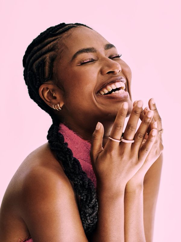 Joyful woman laughing with hands clasped.