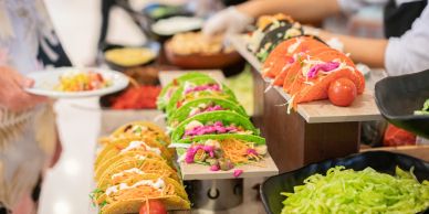 Taco buffet line with various toppings and fillings.