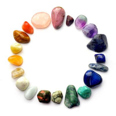 A circle of polished multicolored gemstones arranged on a white background.