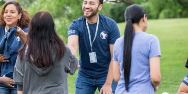 People greeting each other outdoors with smiles.