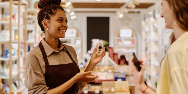 Salesperson showing perfume bottle to customer.