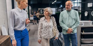 A couple talks with a saleswoman in a bathroom showroom.
