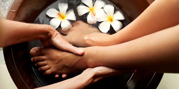 A foot massage in a bowl with floating white flowers.