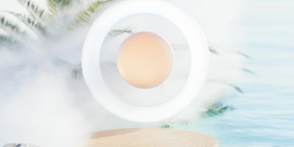 A glowing circular lamp with a soft orange center on a wooden surface near water.