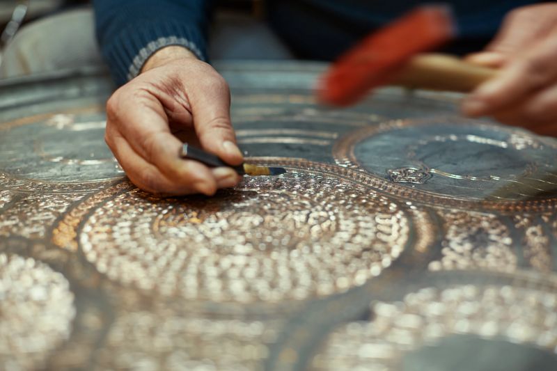 Craftsman doing engravings on a copper metal plate