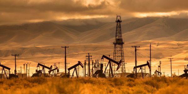 Oil field with pumpjacks under a dramatic sky.