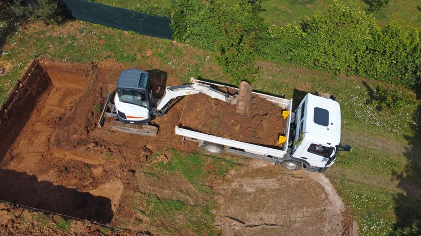 Excavator loading soil into a truck at a construction site.