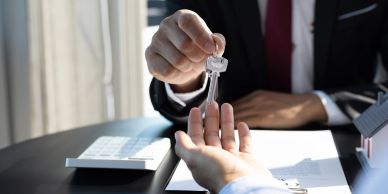A person handing over house keys to another person.