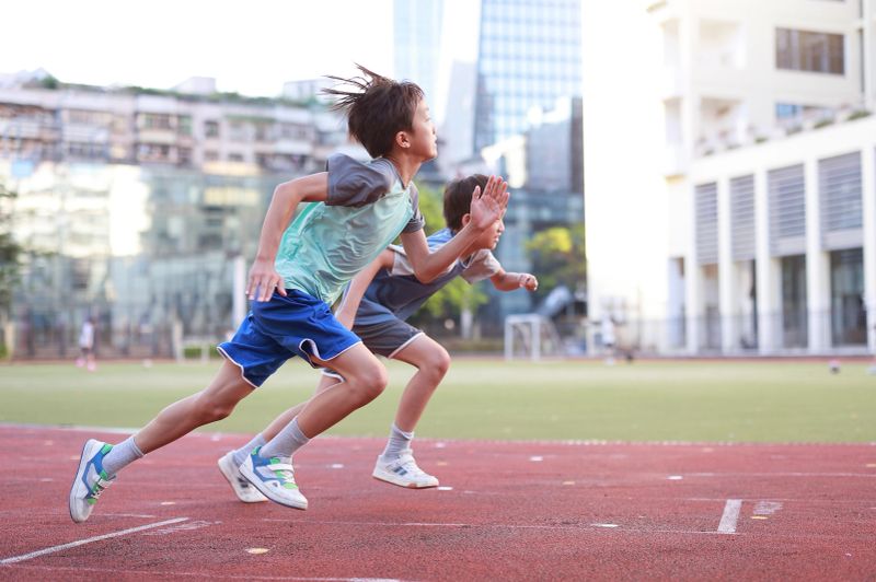 Little boy exercises outdoors on sportsground.In the photo, the sports field is in Shenzhen Cuizhu Foreign Language Experimental School. The buildings are on the street outside the school.Non famous architecture.（14 Dongmen North Road, Luohu District, Shenzhen）