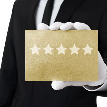 Person in suit holding a gold card with five stars rating.