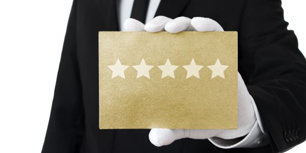 Person in white gloves holding a gold card with five stars.