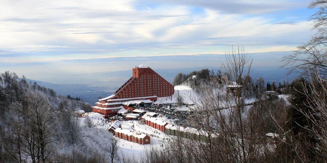A snowy mountain resort with a large triangular building and surrounding smaller houses.