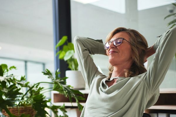 Relaxed woman enjoying a moment in a plant-filled room.