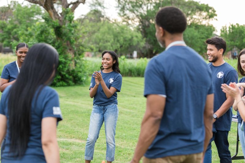 After a successful day, the diverse group of volunteers stand in a circle and clap.