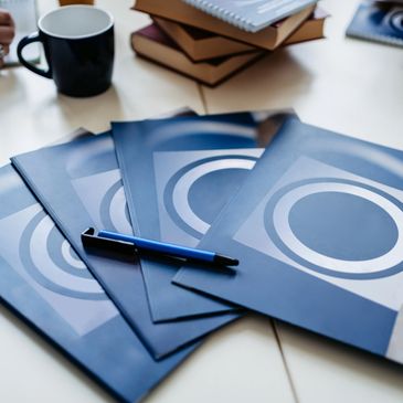 Blue notebooks with circular designs and pens on a meeting table.
