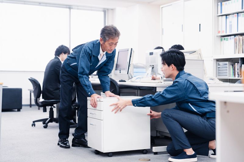 A staff member carrying office furniture